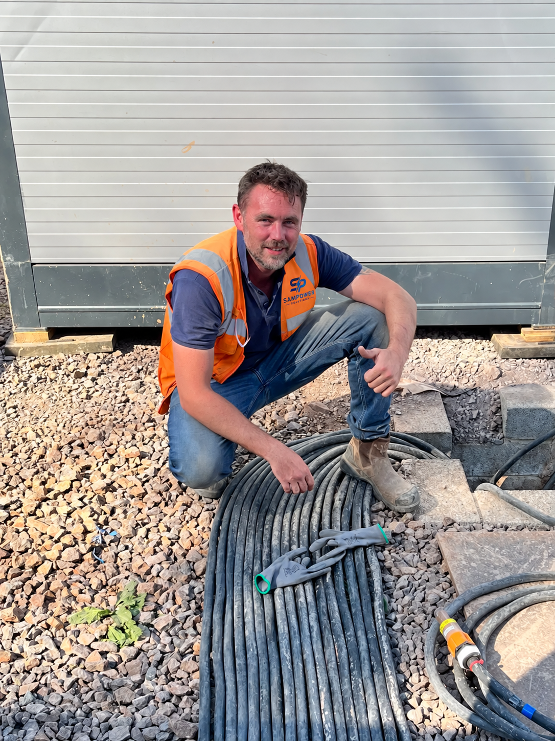 Sam on site alongside heavy-duty temporary power cabling in SamPower Solutions branded safety wear